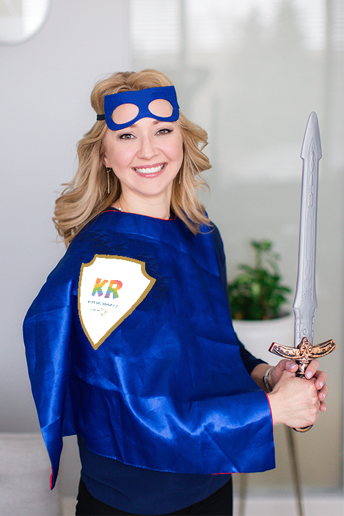 Natalie Bergman, child psychologist, wearing a KR Superhero cape and wielding a silver and gold toy sword
