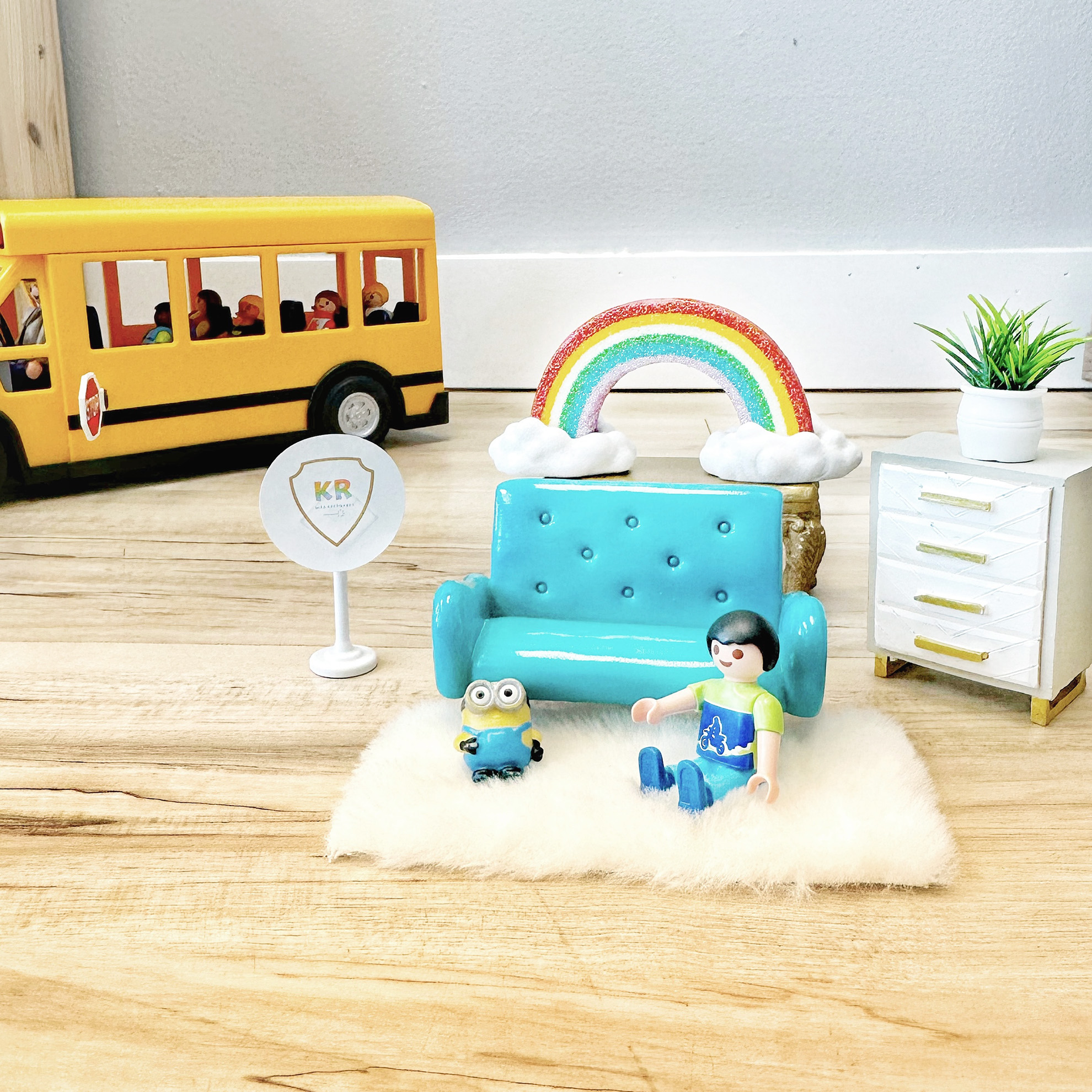 Toys arranged to depict a child in a Kids Reconnect play therapy room, with a toy school bus in the background.