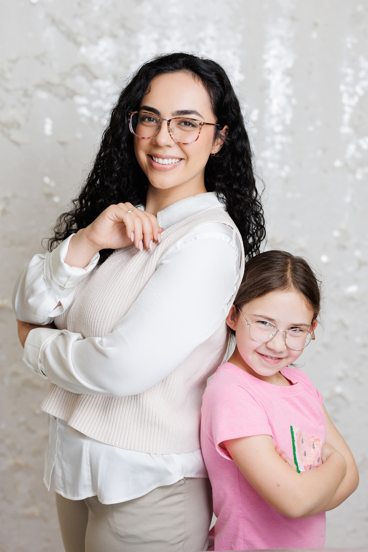 A child therapist and a young girl smilie as they stand with their backs to each other.