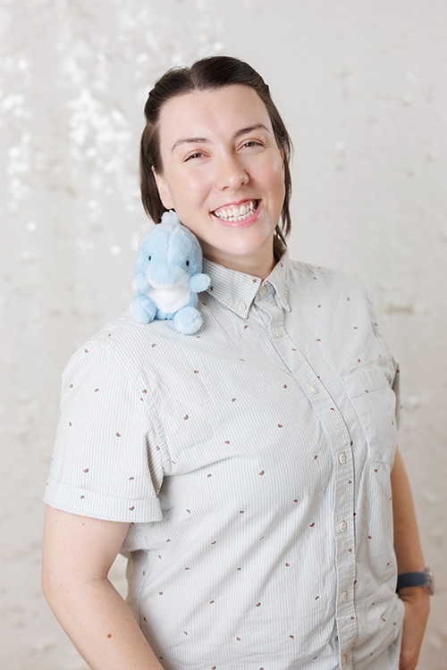 Headshot of Chelsea Houston, MSW, RSW - Kids Reconnect. Chelsea is smiling and has a small blue dolphin stuffy on her shoulder