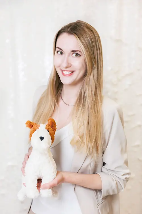 Headshot: Liza (Elizaveta) Eldysheva at Kids Reconnect. Liza is smiling as she holds a dog stuffy.