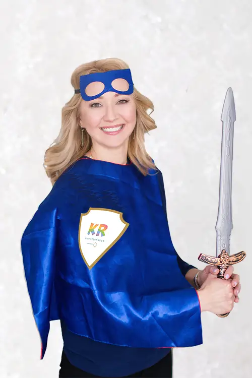 A child psychologist and play therapist (Natalie Bergman) wields a toy sword. She is wearing a cape with the Kids Reconnect logo.