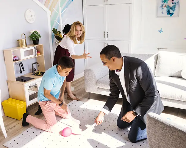 A father and son in a play therapy room with a play therapist at a parent-child counselling session