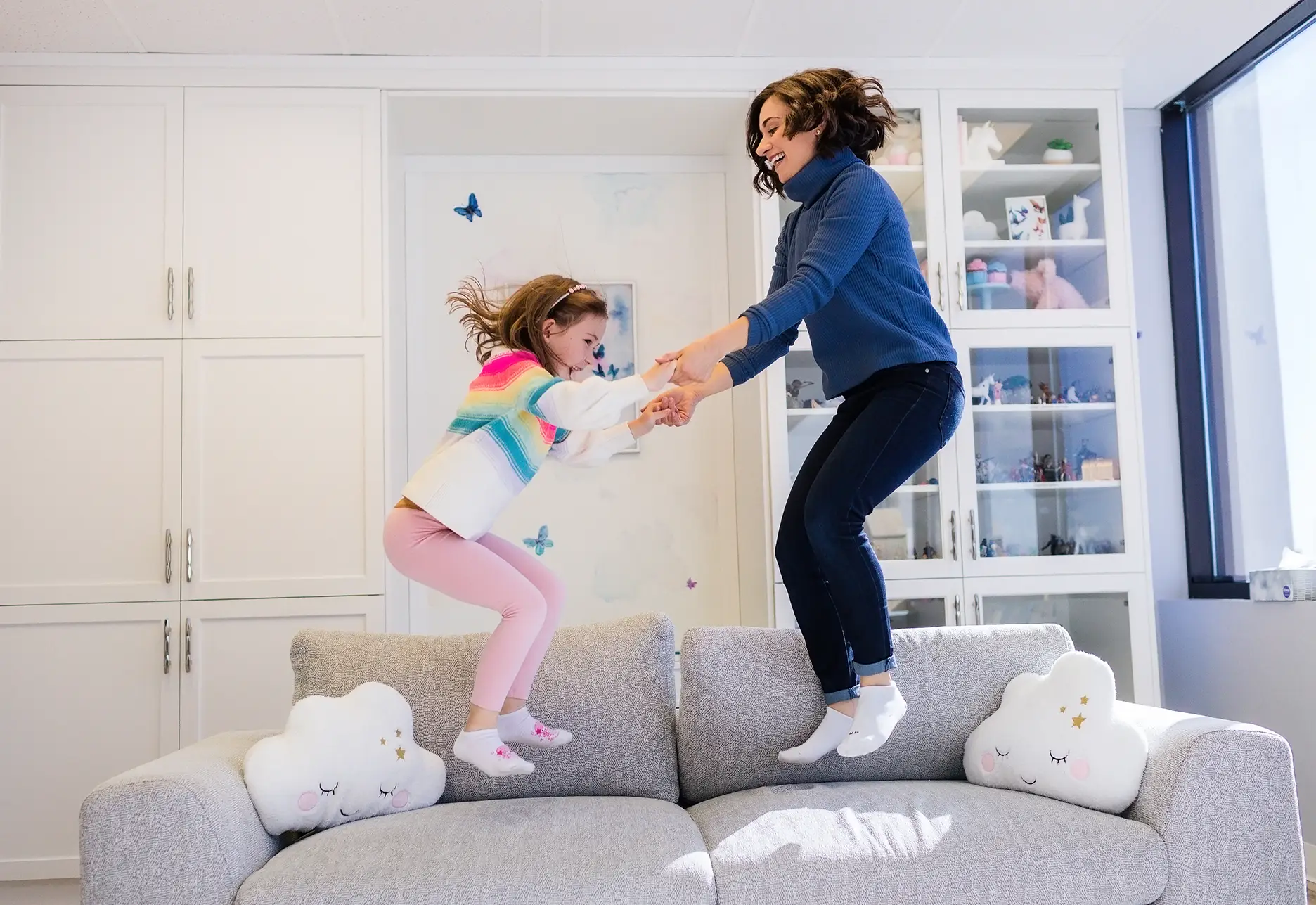 A child and a child psychologist joyfully jumping on a sofa during a play therapy session at Kids Reconnect