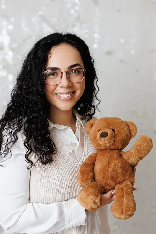 RIta Motta, MSW, RSW, child counsellor at Kids Reconnect, smiles as she holds a teddy bear who is waving his paw to say hi.