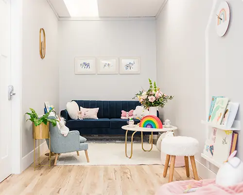 A comfy sofa and child-sized chairs with toys in a child counselling clinic waiting room.