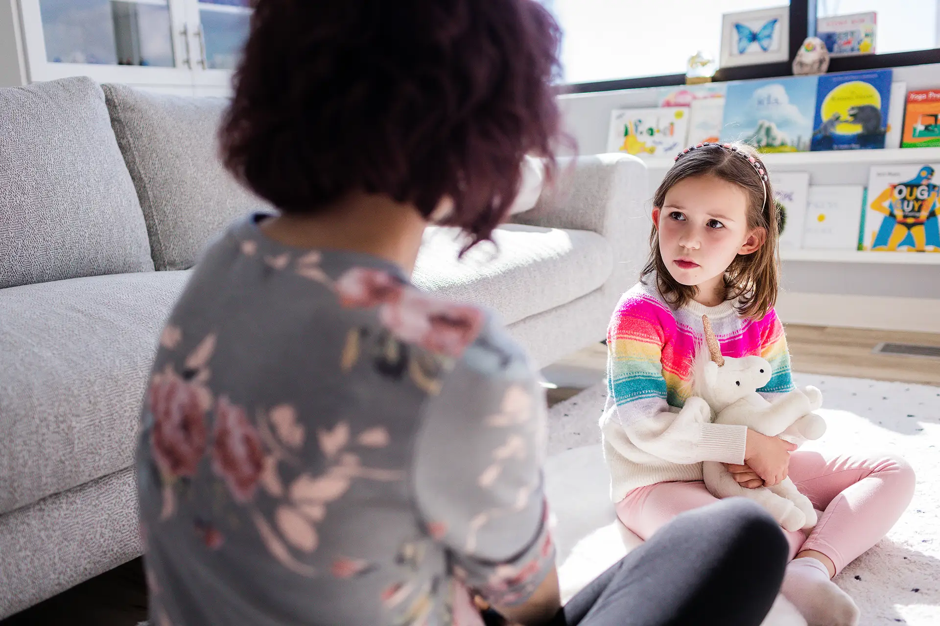 A child hugs a soft toy as she talks to her counsellor