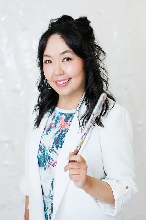 A woman holding a sparkly toy wand. Headshot of Basira Rahimi, Child Therapist at Kids Reconnect.